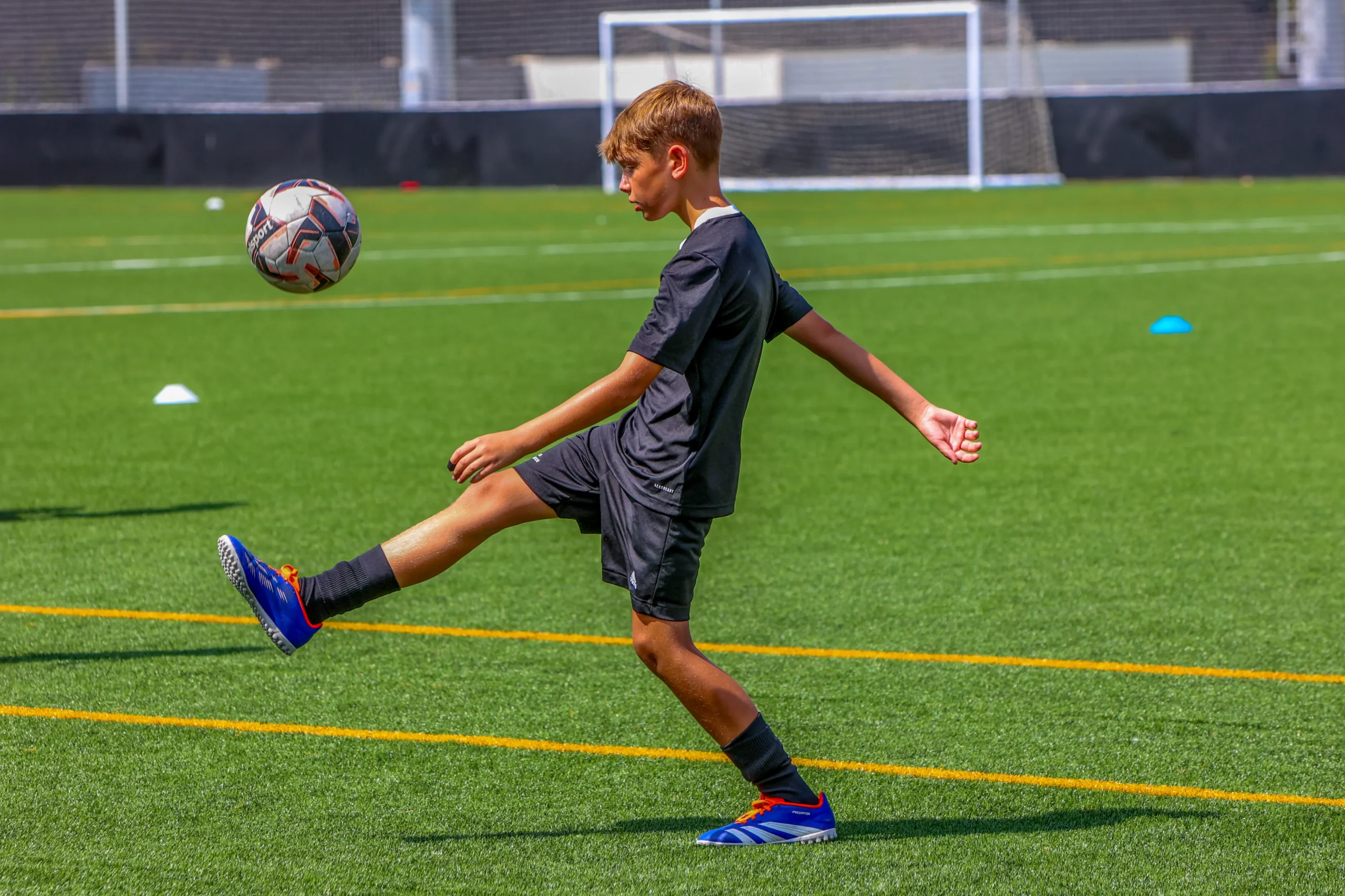 Niño pateando un balón durante un entrenamiento de tácticas en fútbol.
